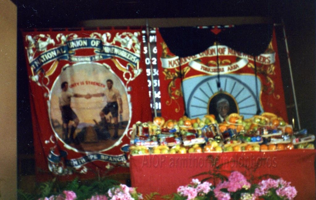 photo a bit blurred,but the only one we have showing both banners.Note the black shroud on the one on right,to commemorate those who died at M.M.-Made by DOLLY GOFFIN